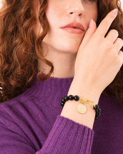Bracciale elastico con sfere in vetro nere e medaglietta in metallo